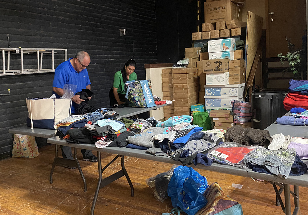 Fr. Gustavo Meneses sorts and folds clothes for migrants May 13 at a temporary shelter the Diocese of El Paso set up to care for migrants at Our Lady of Assumption Parish in El Paso, Texas. The diocese has been working with local governments and organizations to prepare for an influx of migrants in the border city. (NCR photo/Rhina Guidos)