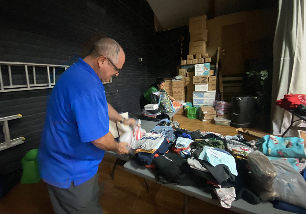 Fr. Gustavo Meneses arranges clothes for migrants May 13 at a temporary shelter the Diocese of El Paso set up to care for migrants at Our Lady of Assumption Parish in El Paso, Texas. Meneses, a member of the Dicastery for Promoting Integral Human Development, who lives in Costa Rica, arrived in El Paso to help the border diocese as some predicted an overwhelming influx of migrants. (NCR photo/Rhina Guidos)