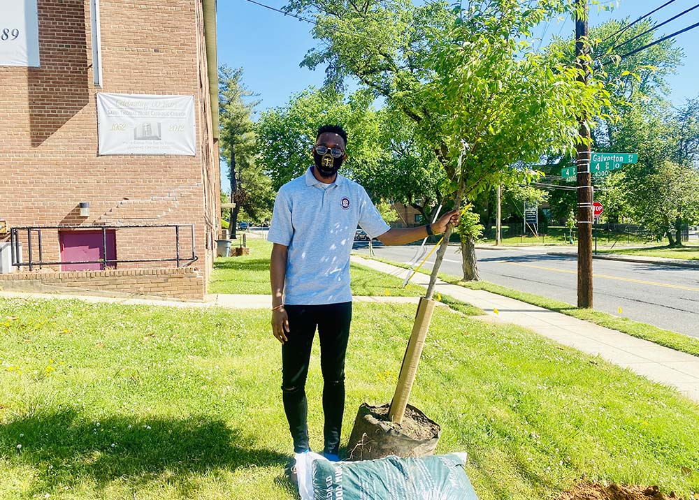 Gerald Smith, principal at St. Thomas More Academy in Washington D.C., poses with one of the 88 trees planted at the Catholic school in May 2021 through the Laudato Trees program. (Courtesy of St. Thomas More Academy)