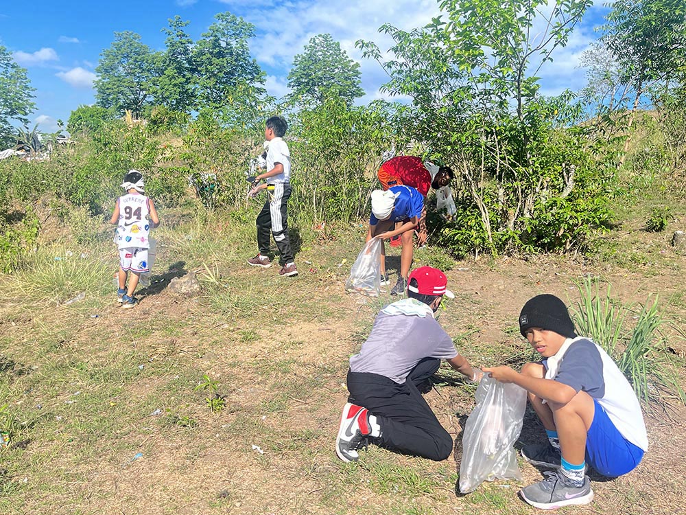 Teens and children pick up trash in Sitio Bakal, a field outside Quezon City, Philippines, as part of a local Run4Unity event. (Fralynn Ibanez Manalo)