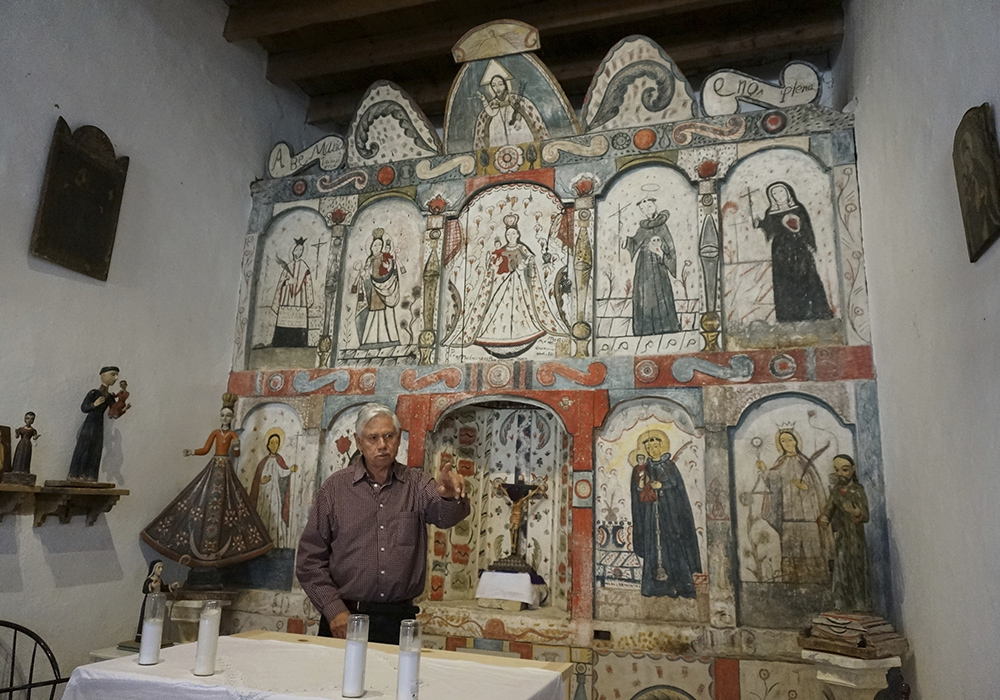 Master santero Felix Lopez — an artist trained in New Mexico's centuries-old tradition of religious sculpture and painting — speaks during an interview while standing in front of the 1810s reredo or altarpiece he cleaned and preserved in the Holy Rosary Mission Church April 16 in Truchas, New Mexico. (AP photo/Giovanna Dell'Orto)