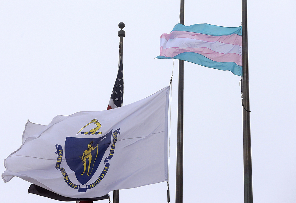 A flag representing the transgender community, foreground, flies next to the Massachusetts state flag and a U.S. flag in front of Boston City Hall in 2016. (AP/Steven Senne)