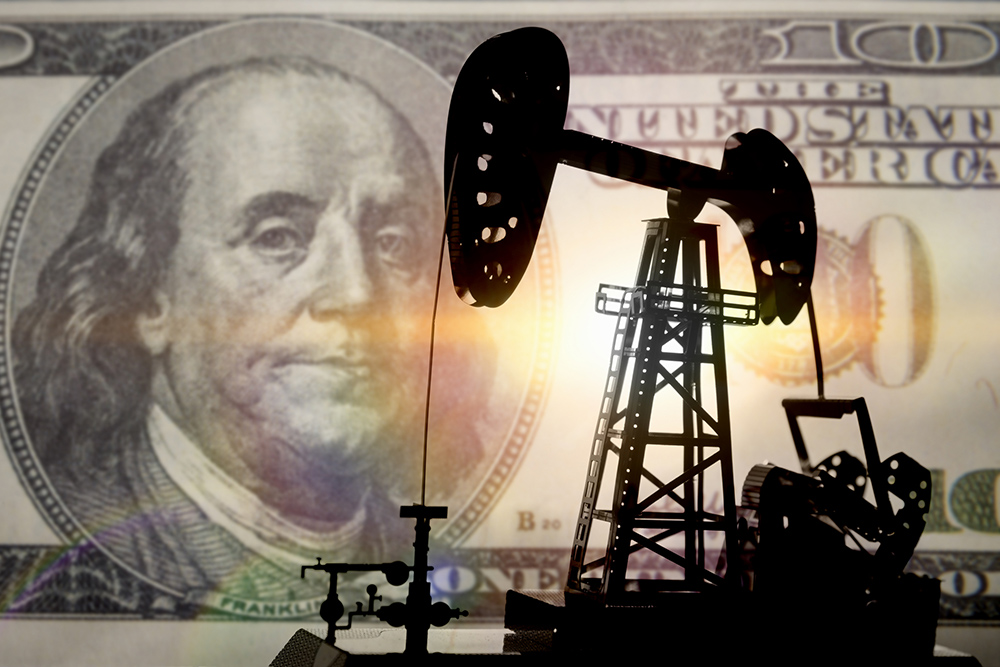 Silhouette of an oil drill against a $100 bill (Dreamstime/Mrsash174)