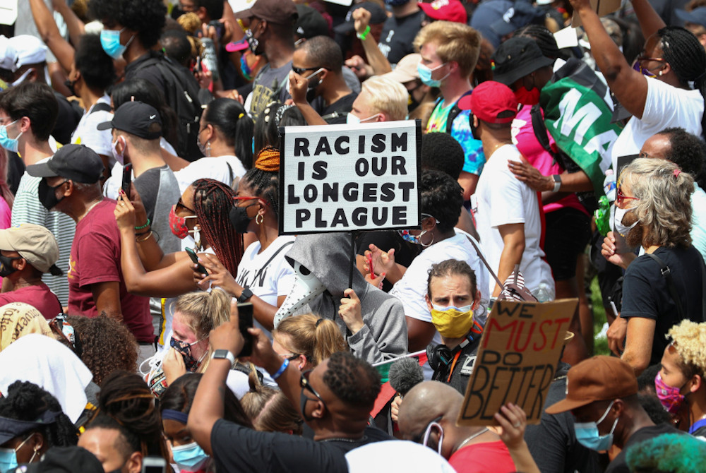 Protesters stand with a sign reading "Racism Is Our Longest Plague" in Washington Aug. 28, 2020, during the "Get Your Knee Off Our Necks" Commitment March on Washington 2020 in support of racial justice. (CNS/Reuters/Tom Brenner)