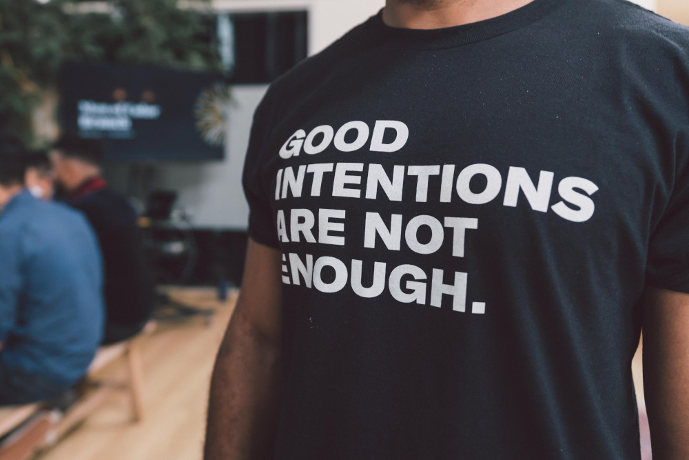 A person wearing a shirt that says "Good intentions are not enough." (Unsplash/Edgar Chaparro)