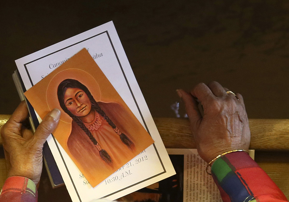 A woman holds a likeness of St. Kateri Tekakwitha — a 16th-century Mohawk-Algonquin woman known as the "Lily of the Mohawks" — during a special Mass commemorating her canonization at St. Francis Xavier Church, where she is buried, in Kahnawake, Quebec, Oct. 21, 2012. (CNS/Reuters/Christinne Musch)