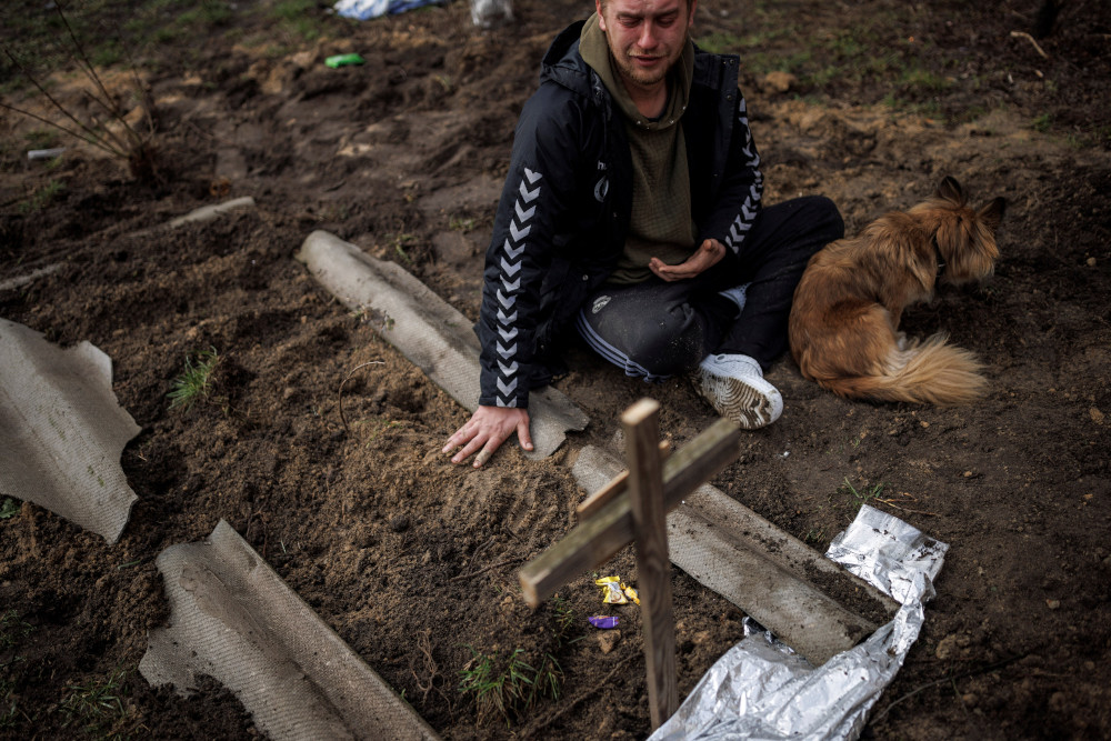 Serhii Lahovskyi, 26, mourns next to the grave of his friend, Ihor Lytvynenko, after he was beside a building's basement in Bucha, Ukraine, April 6, 2022. Residents say the man was killed by Russian soldiers. (CNS/Reuters/Alkis Konstantinidis)