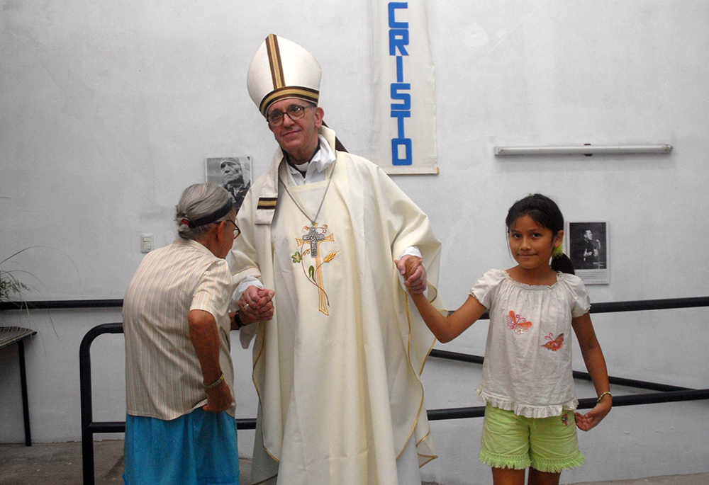 Argentine Cardinal Jorge Mario Bergoglio holds the hands of a woman and girl during Holy Thursday Mass in 2008 at a church in a poor section of Buenos Aires, Argentina. Bergoglio was later elected pope March 13, 2013, becoming the first pope to take the name of St. Francis of Assisi. (CNS/Reuters/Enrique Garcia Medina)