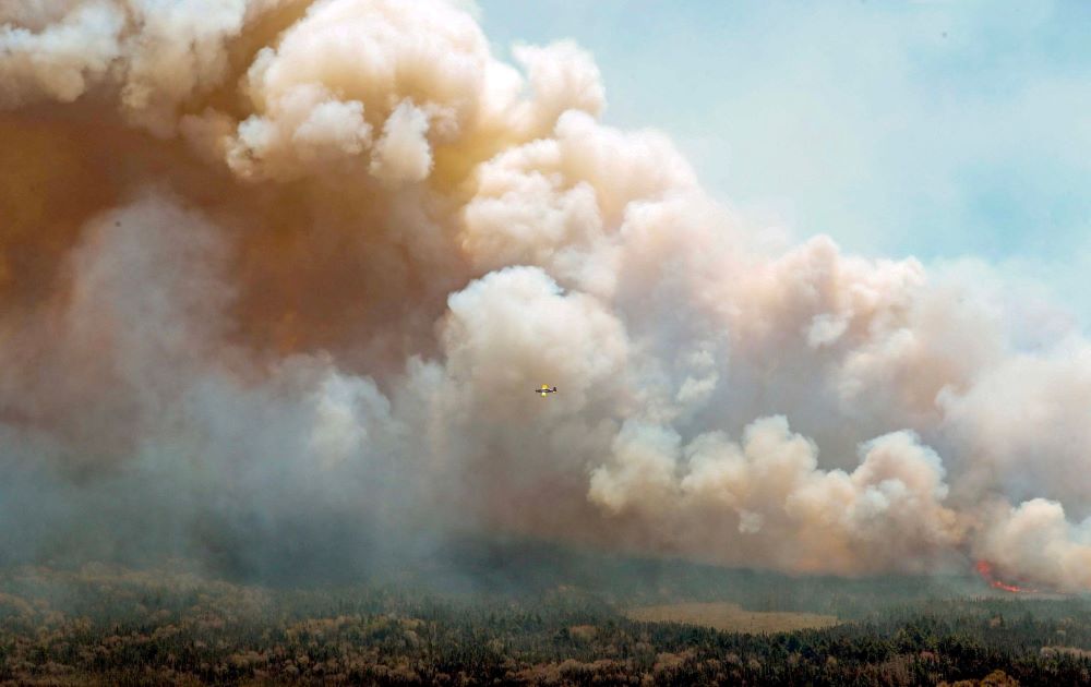 In Canada, a New Brunswick aircraft drops a mix of water and fire retardant as it passes over a wildfire in Barrington Lake, Nova Scotia, in this social media handout image released May 31, 2023. (OSV News photo/Nova Scotia Government handout via Reuters)