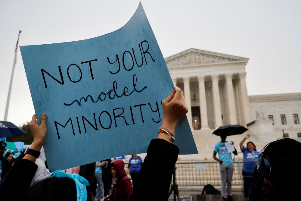 Demonstrator holds sign outside Supreme Court. It reads, "Not your model minority."