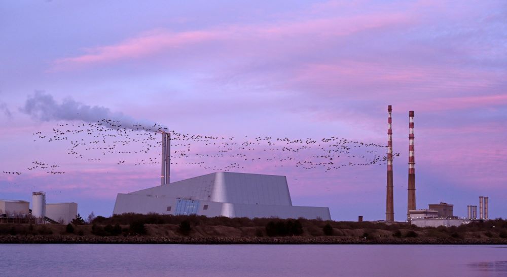 A flock of geese fly past the Poolbeg Generating Station chimney stacks at sunset in Dublin Feb. 21, 2021. The Irish Catholic Bishops' Conference was the first bishops' conference in the world to divest their assets from fossil fuels. (CNS/Reuters/Clodagh Kilcoyne)