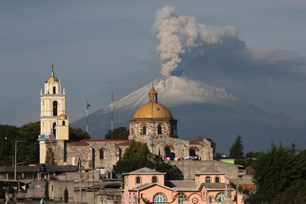 The main church in the town of San Damian Texoloc, Mexico stands in front of the Popocatepetl volcano as is spews ash and vapor early July 9, 2013.
