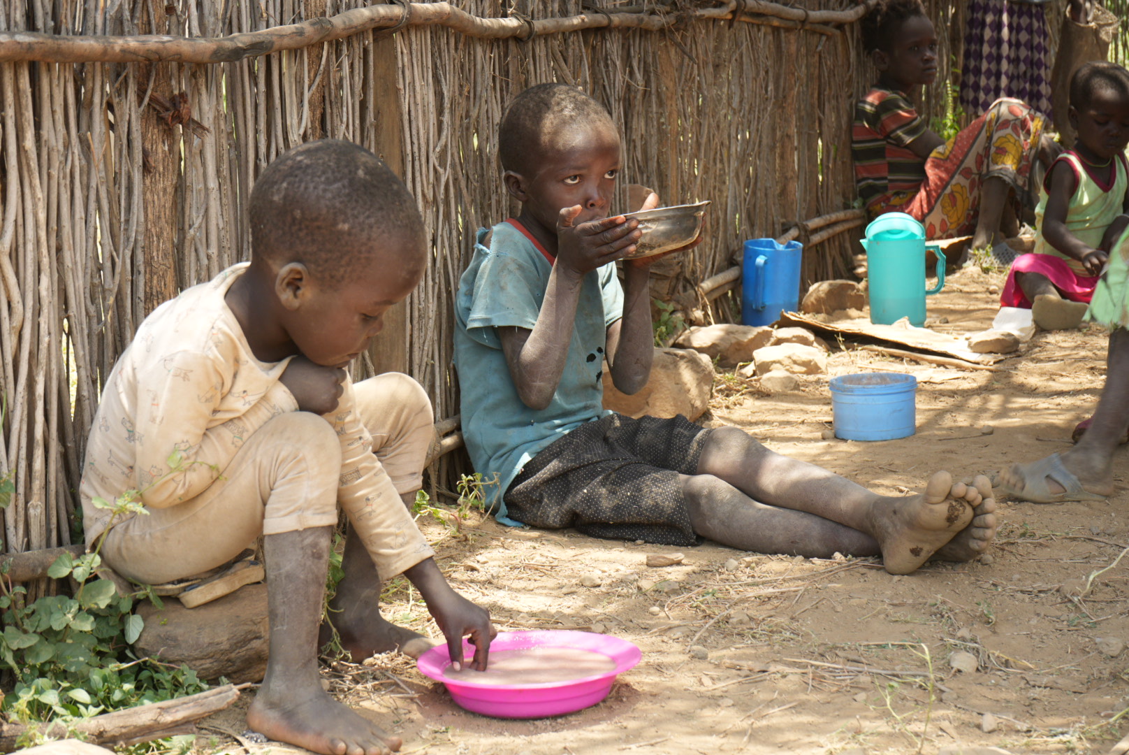 Children eat porridge as they seek refuge from the scorching sun at the Incarnate Word Sisters' compound in Rotu village. High levels of poverty, insecurity, and the ongoing drought have resulted in widespread food insecurity for most families. The missionary sisters provide porridge to the children each morning to help ease the pressure of hunger in East Pokot's families. (GSR photo/Wycliff Peter Oundo)