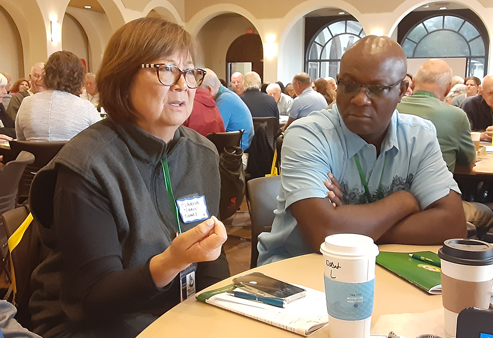 Clarisa Gomez of San Diego explains her ministry in the context of synodality during a table discussion during the annual assembly of the Association of U.S. Catholic Priests on June 14 at the University of San Diego. At right is Fr. Kwane Assenyoh, parochial administrator of St. Charles Borromeo Parish, Livermore, California. (Dennis Sadowski)