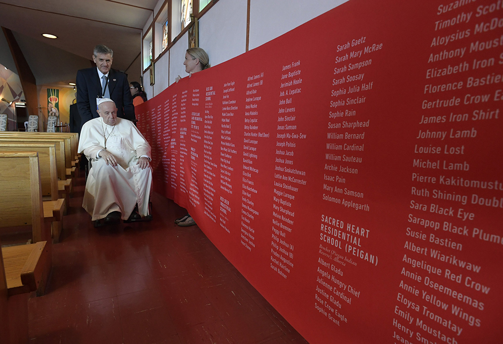 Pope Francis prays in front of a banner bearing the names of each of the 4,120 Indigenous children and the residential school where they died, in this photo from his visit to Maskwacis, Alberta, July 25, 2022. (CNS/Vatican Media)