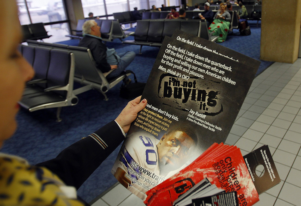 A flight attendant carries educational materials to help airline personnel spot sex trafficking through the Dallas Fort Worth International Airport in Dallas ahead of NFL football's Super Bowl XLV in 2011. Advocates for trafficking victims say big events like the Super Bowl and events surrounding them are a "danger zone" for sex and labor trafficking and domestic violence." (OSV News/Reuters/Brian Snyder)