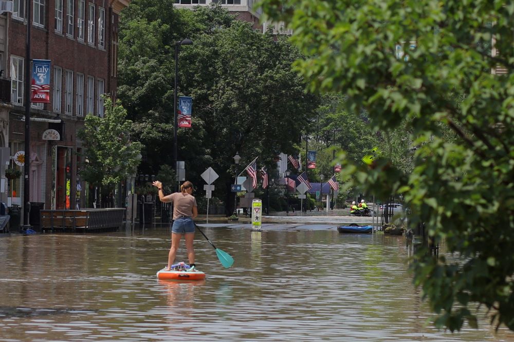 A woman rows a paddle board in a flooded area in Montpelier, Vt., July 11, 2023. 