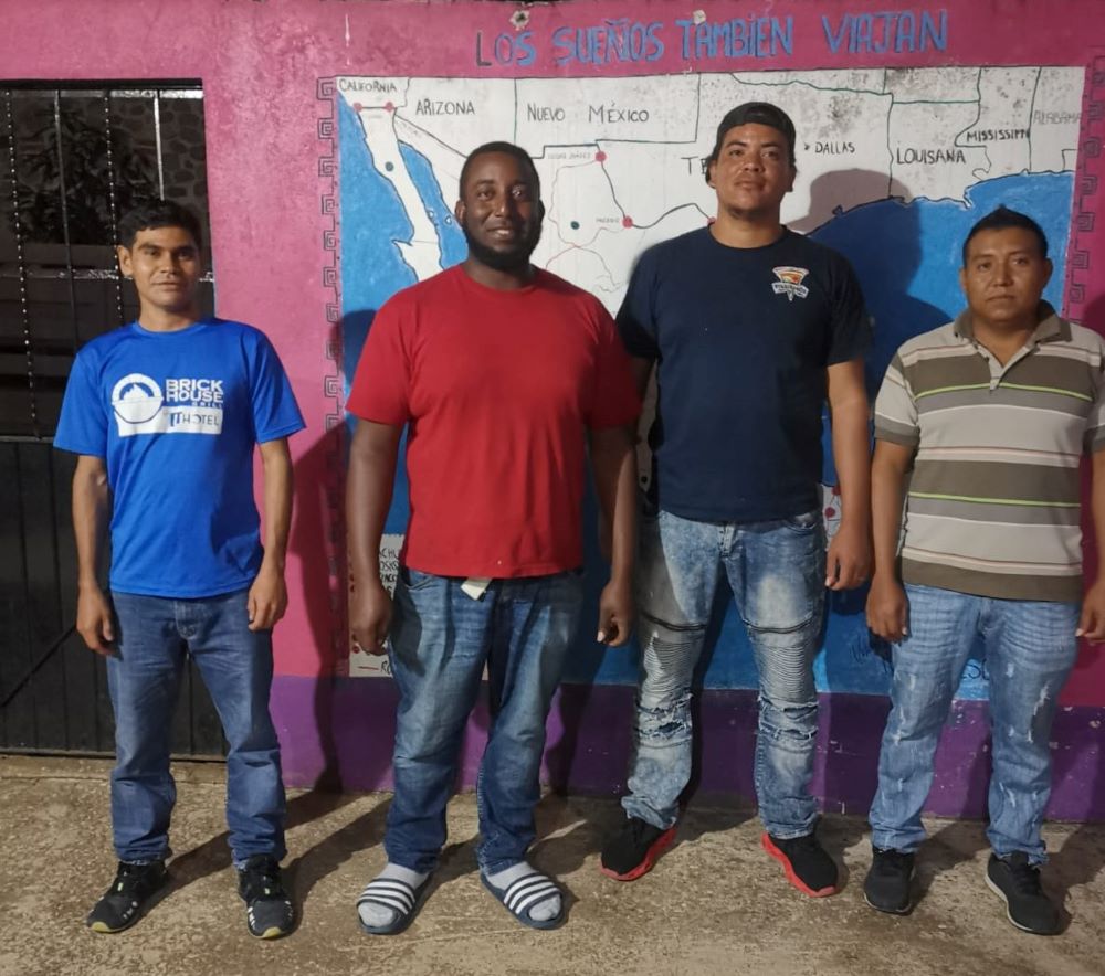 Young migrants who applied for asylum to stay in Mexico pose in front of a map of migration routes. (Courtesy of Las Patronas)