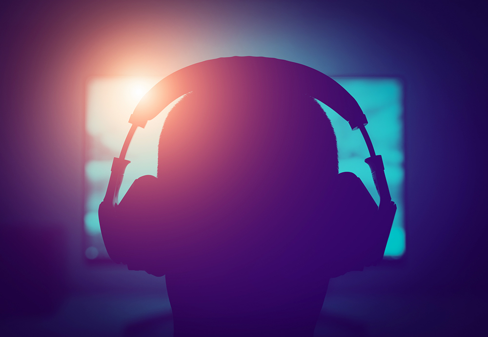 Silhouette of a gamer wearing headphones in front of a screen (Dreamstime/Darkworx)