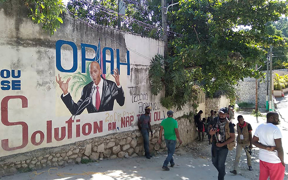 Un grupo de personas pasa junto a una pared con un mural que representa al presidente de Haití, Jovenel Moïse, el 7 de julio de 2021 en Puerto Príncipe. Moïse fue asesinado en un atentado en la madrugada del 7 de julio de 2021 en su domicilio a las afueras de la capital, Puerto Príncipe, informó el primer ministro. (Foto: CNS/Reuters/Robenson Sanon)