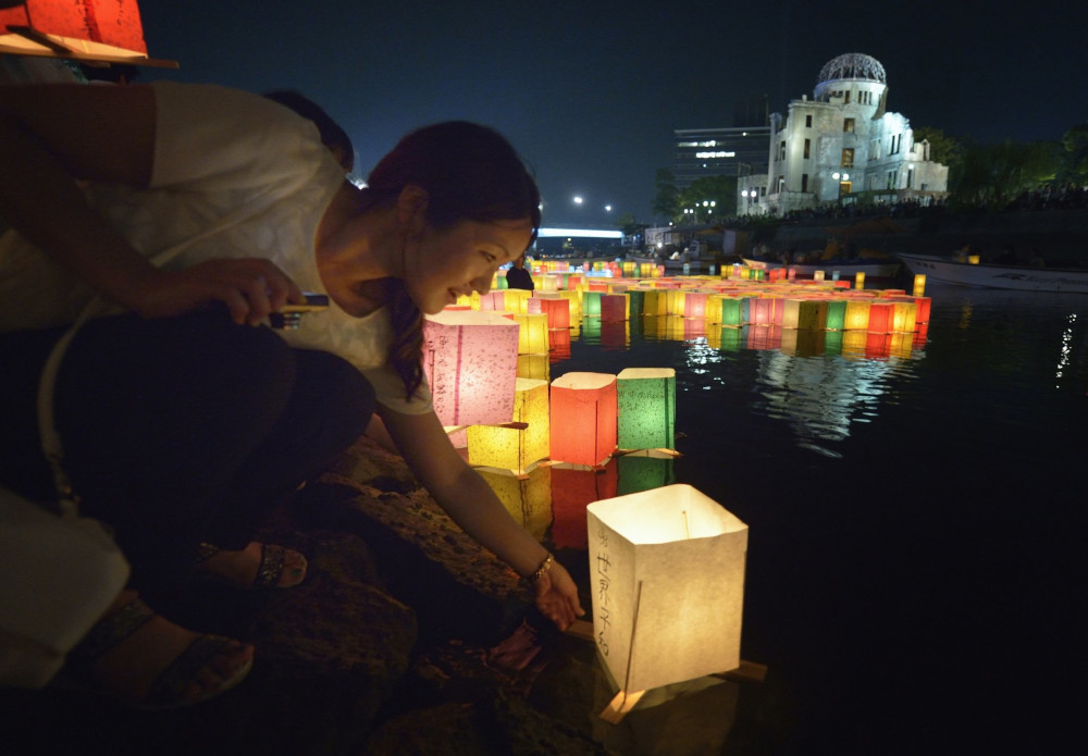A woman sets a floating candle lantern on the river Aug. 6, 2015, in Hiroshima, Japan. (CNS photo/Paul Jeffrey)