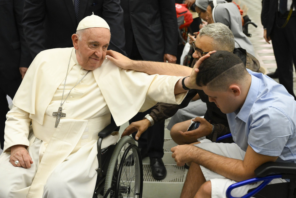 Pope Francis, seated in his wheelchair, blesses a young man seated in a wheelchair at the end of his weekly general audience Aug. 9, 2023, in the Vatican audience hall. (CNS photo/Vatican Media)