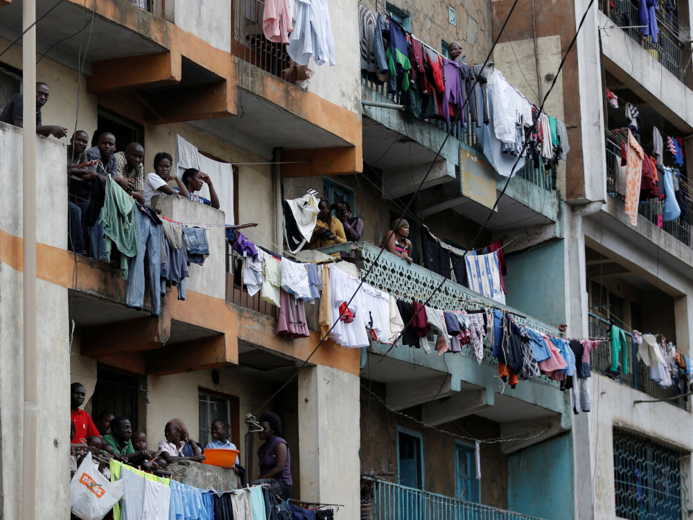 Many people gather on apartment balconies where clotheslines full of clothes also hang