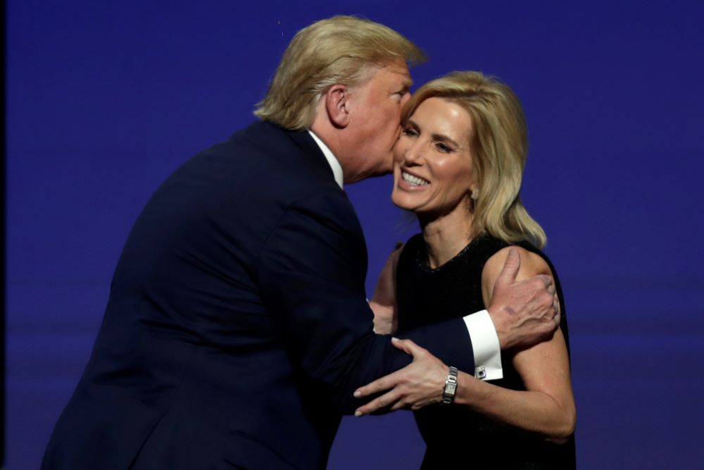 Then-President Donald Trump gives Laura Ingraham a kiss after inviting her on stage during the Turning Point USA Student Action Summit at the Palm Beach County Convention Center, on Dec. 21, 2019, in West Palm Beach, Fla. After Trump was indicted on four charges Aug. 1, Ingraham invoked his right to free speech. (AP/Luis M. Alvarez, file)