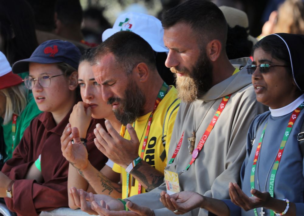 Pilgrims pray during the welcome ceremony for Pope Francis during World Youth Day at Eduardo VII Park in Lisbon, Portugal, Aug. 3. (OSV News/Bob Roller)