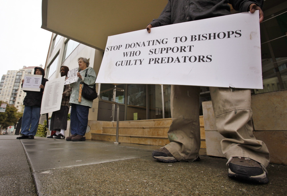 A person holds a sign that reads, "stop donating to bishops who support guilty predators."