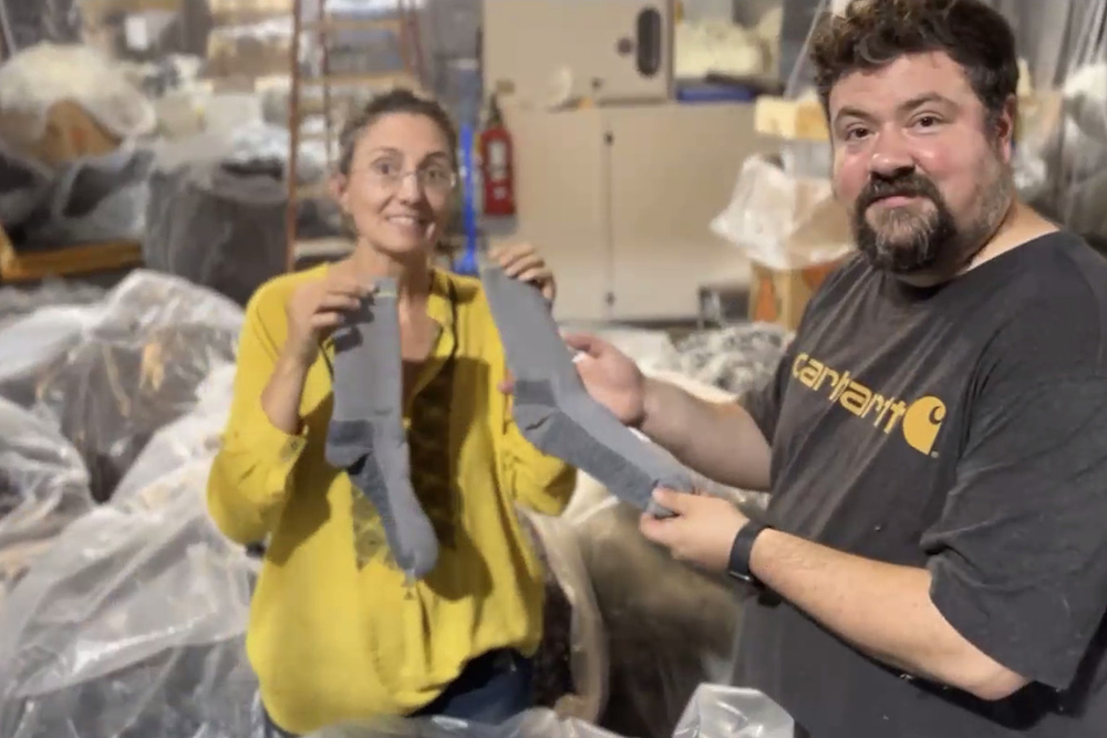 Molly Hemstreet and Bob Carswell of The Industrial Commons showcase a pair of socks made from yarn recycled from old socks as part of the Second Cuts Project. Based in North Carolina, The Industrial Commons was honored as a Laudato Si' Champion in business during the "Laudato Si' and the U.S. Catholic Church" conference on July 27. (NCR screenshot)