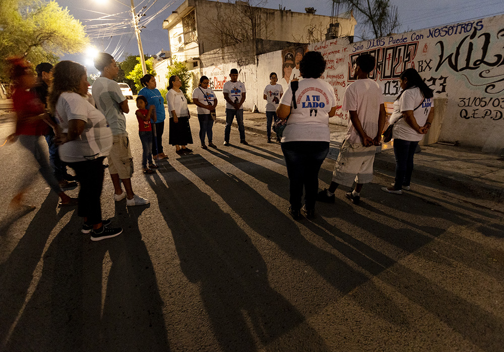 La Hna. Sándra López García, la Hna. Sanjuana Morales Nájera y el equipo de laicos misioneros rezan ante un monumento dedicado a dos miembros de la banda Los Bronx, quienes murieron recientemente en un accidente de moto. (Foto: GSR/ Nuri Vallbona)