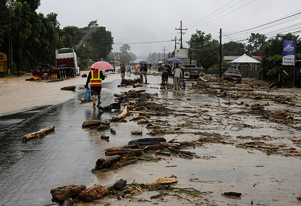People walk through debris in a road in Toyos, Honduras, Nov. 4, 2020, following Hurricane Eta. Crop loss has followed major tropical storms, as was the case in November 2020, when twin Category 4 hurricanes, Eta and Iota, struck Honduras days apart. (CNS/Reuters/Jorge Cabrera)
