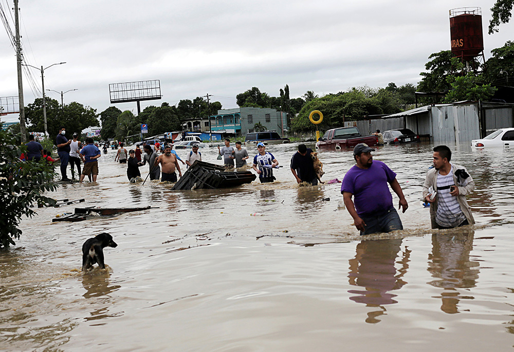 People wade through floodwaters in La Lima, Honduras, Nov. 5, 2020, in the rain-heavy remains of Hurricane Eta. (CNS/Reuters/Jorge Cabrera)