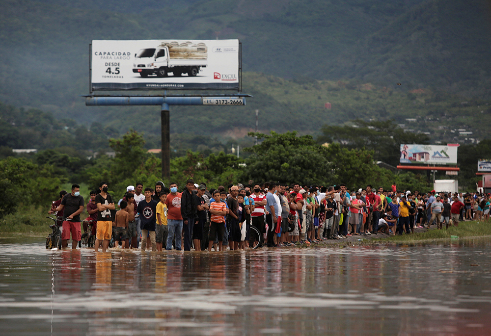 People stand alongside floodwaters in La Lima, Honduras, Nov. 5, 2020, in the remains of Hurricane Eta. (CNS/Reuters/Jorge Cabrera)