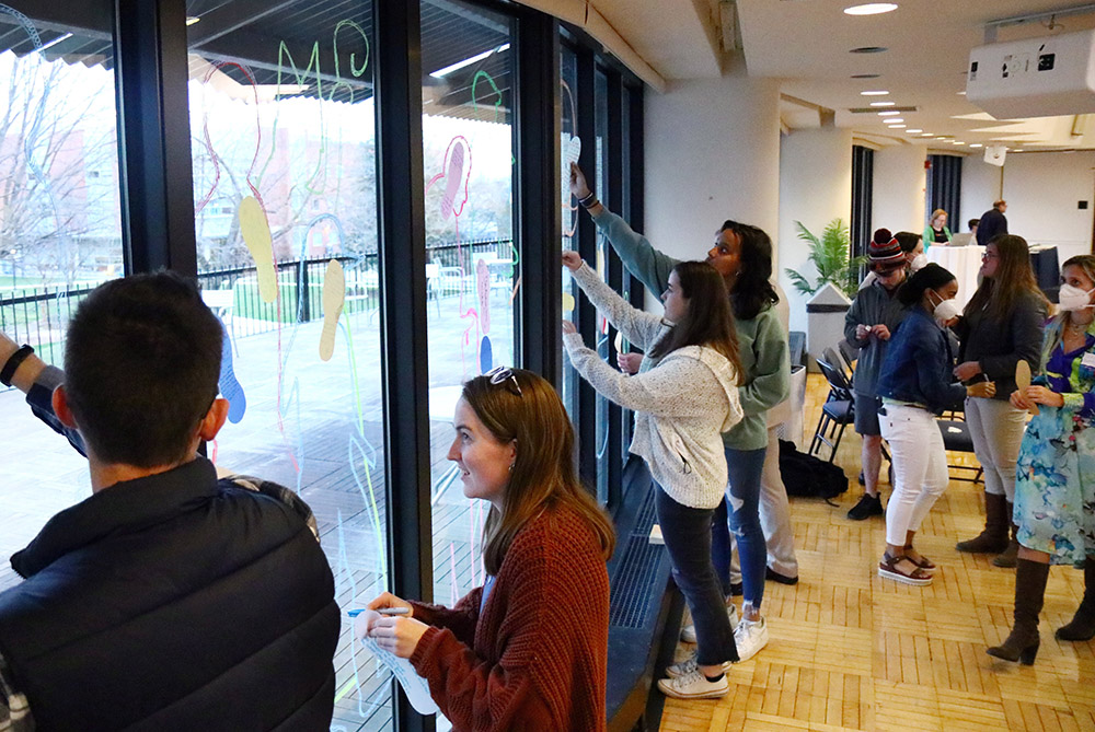 Participants in a synod listening session at La Salle University in Philadelphia write messages about the experience April 4, 2022, and attach them to the windows of a conference room for passersby to read. (CNS/CatholicPhilly.com/Sarah Webb)