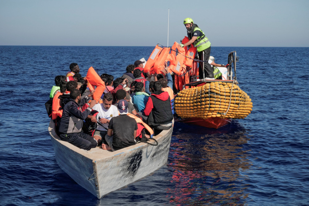 Crew members from the NGO rescue ship Ocean Viking give lifejackets to migrants on an overcrowded boat in the Mediterranean Sea Oct. 25, 2022. (CNS photo/Camille Martin Juan/Sos Mediterranee/handout via Reuters)