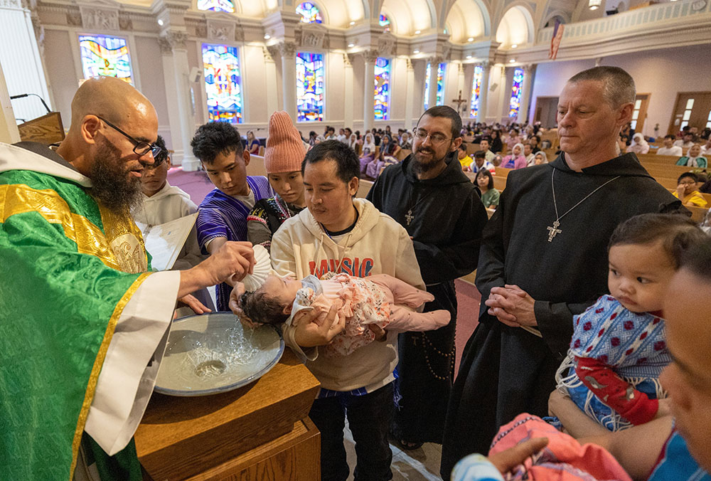 Fr. Seraphim Wirth, a member of the Franciscan Brothers of Peace, baptizes a baby from the Karen community during Mass at St. Casimir Church in St. Paul, Minnesota, Sept. 11, 2022. (CNS/The Catholic Spirit)