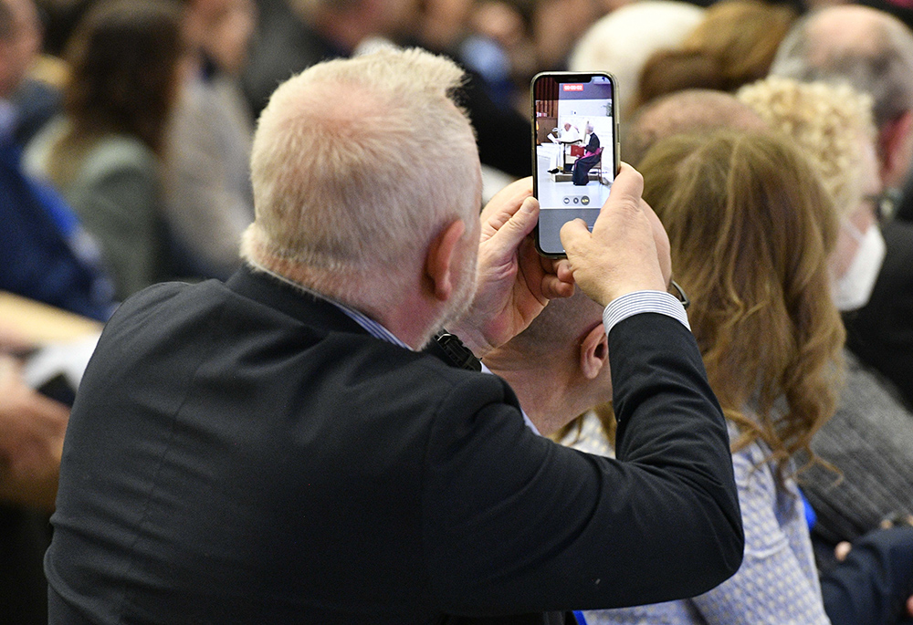 A man takes a video as Pope Francis speaks to members of the Italian bishops' conference and diocesan leaders involved in Italy's national synod process May 25, 2023, in the Vatican audience hall. The pope addressed questions and concerns members of the group submitted about his notion of fostering a "synodal church." (CNS/Vatican Media)