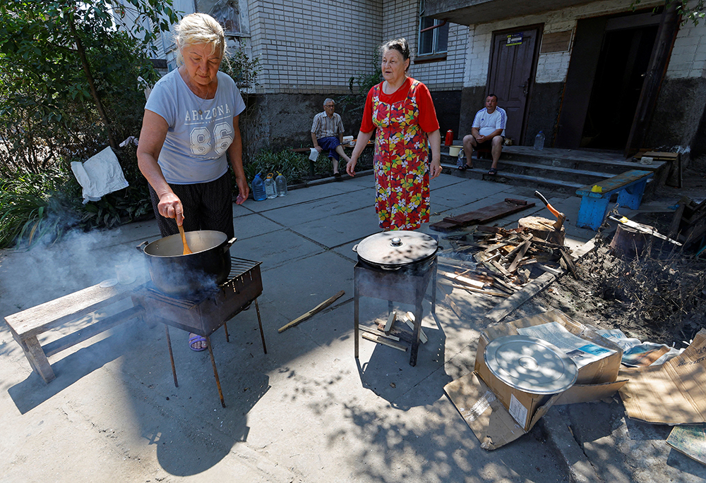 Local residents cook food outside an apartment building in the town of Hola Prystan in the Kherson region, Russian-controlled Ukraine, June 17, after floodwaters receded following the collapse of the Nova Kakhovka Dam in the course of Russia-Ukraine conflict. (OSV News/Reuters/Alexander Ermochenko)