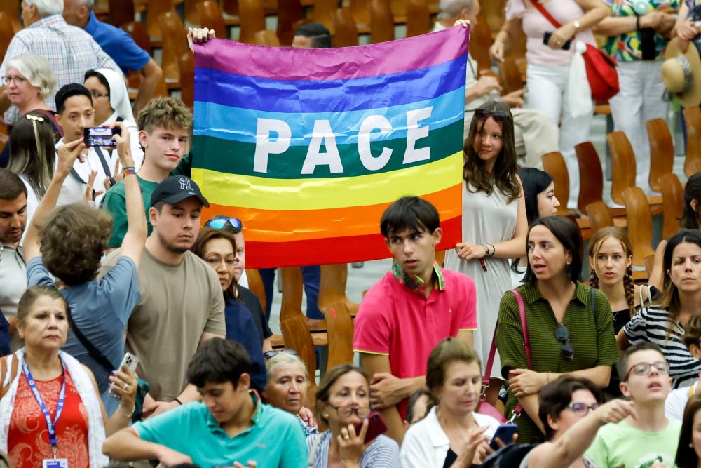 Young people hold a flag reading "peace" in Italian at the end of Pope Francis’s weekly general audience in the Paul VI Audience Hall at the Vatican Aug. 23, 2023. (CNS photo/Lola Gomez)