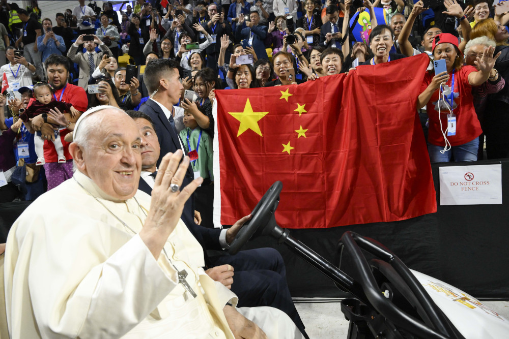 Pope Francis waves as people behind him raise a Chinese flag before the pope's Mass in Steppe Arena in Ulaanbaatar, Mongolia, Sept. 3, 2023. (CNS photo/Vatican Media)