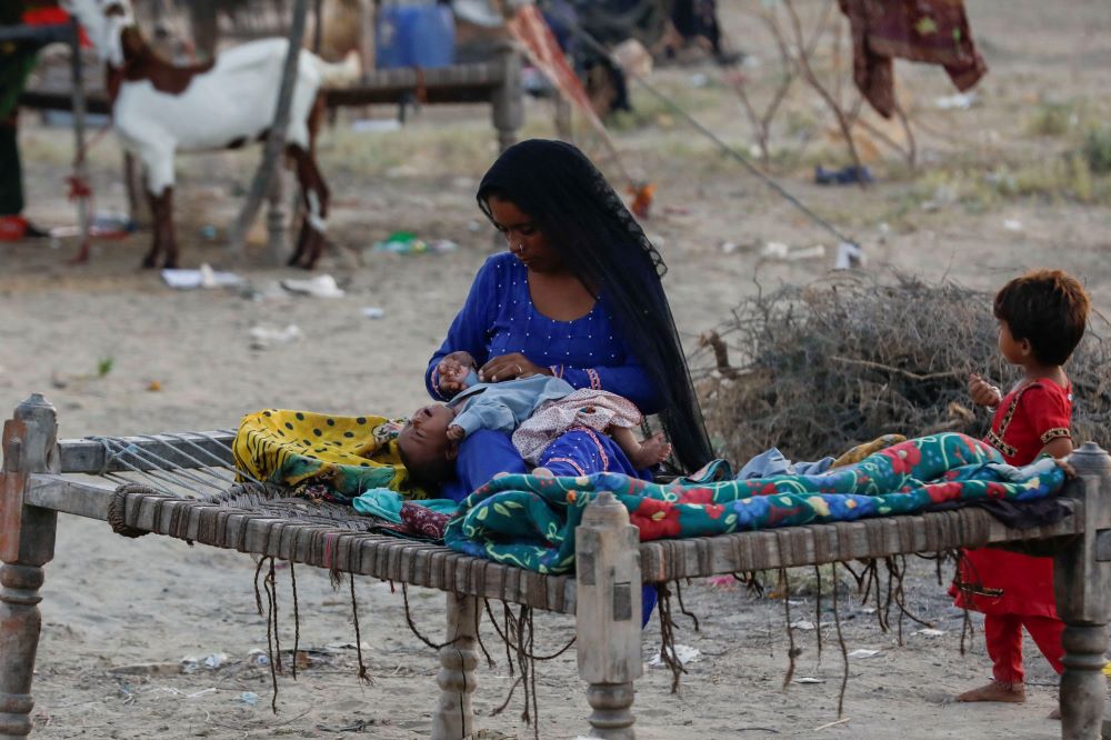 A woman who became displaced following rains and floods during the monsoon season takes care of her baby outside at a camp in Sehwan, Pakistan, Sept. 13, 2022. (OSV News/Reuters/Akhtar Soomro)