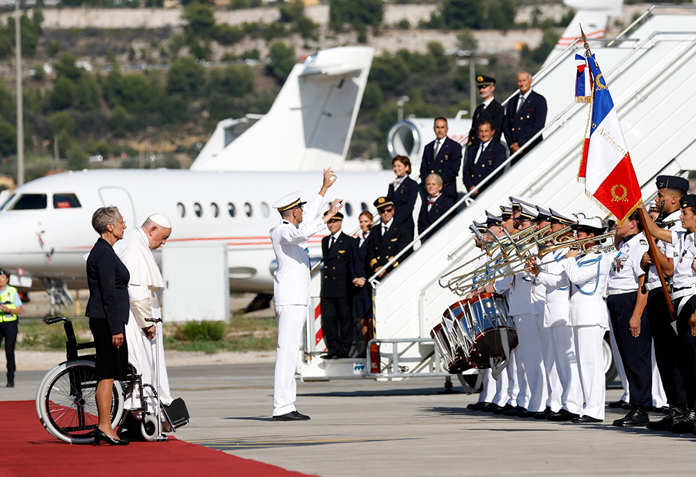 Pope Francis stands with French Prime Minister Élisabeth Borne while the French and Vatican national anthems are played after the pope arrived at Marseille International Airport Sept. 22 in Marseille, France. (CNS/Lola Gomez)
