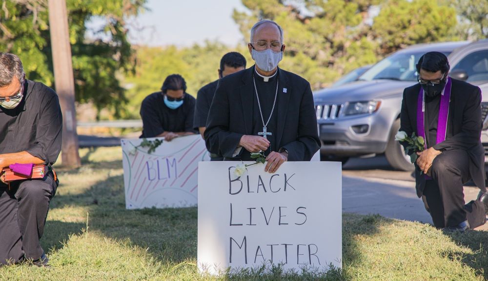 Bishop Mark Seitz of El Paso, Texas, kneels at El Paso's Memorial Park holding a "Black Lives Matter" sign June 1, 2020. Seitz said his diocese is struggling to find a victim assistance coordinator with the appropriate skills to work with people of color. (CNS/Courtesy of Diocese of El Paso/Fernie Ceniceros)