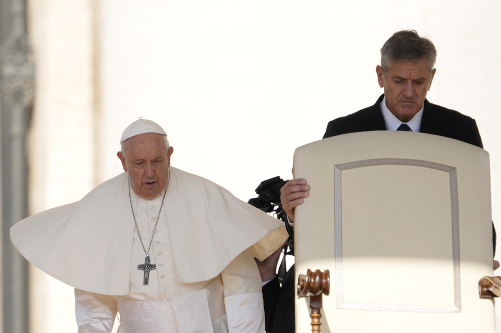 Pope Francis' mozzetta flies out in the wind as he walks beside a white chair