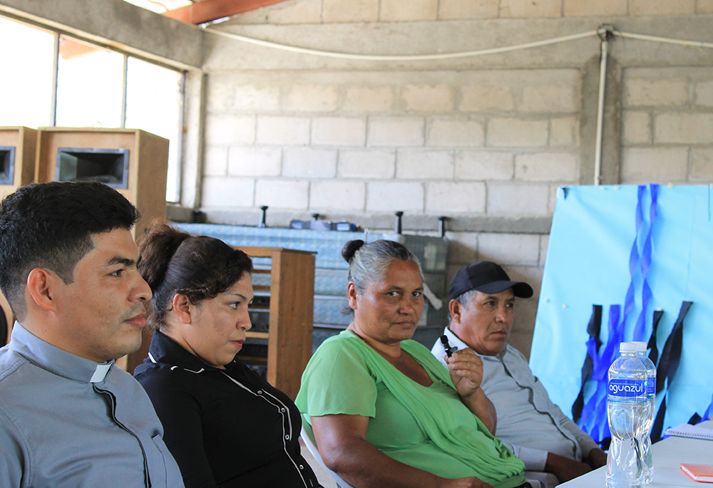 Members of the Fe y Esperanza neighborhood group, including Gabriela Morales (second from right) are seen seated during a meeting with the deputy mayor (not pictured) and Fr. Luis Melquiades (far left). Morales called migration "a family problem." (NCR photo/Brian Roewe)