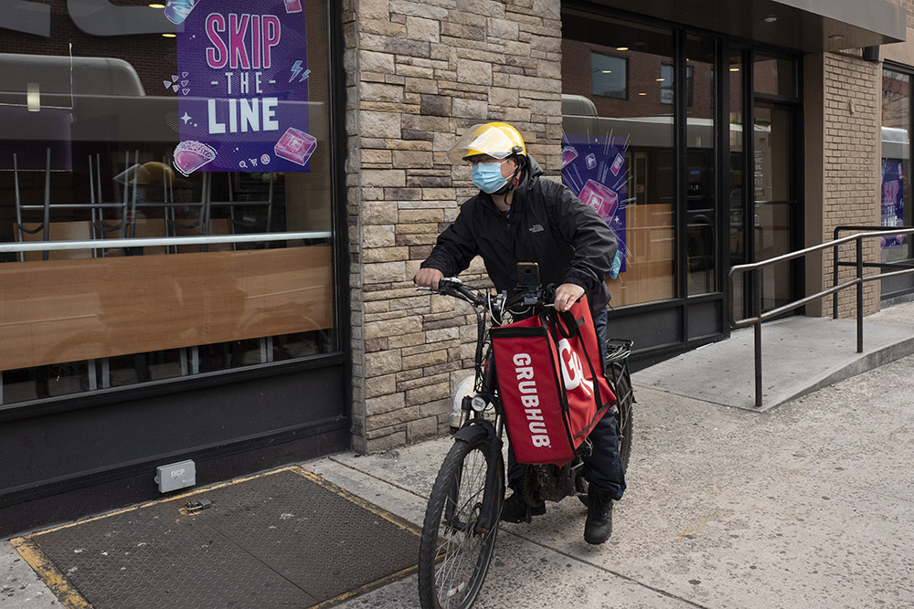 A delivery man bikes with a food bag from Grubhub on April 21, 2021, in New York. Uber Eats, DoorDash and Grubhub sued New York City on July 6, 2023, to block its new minimum pay rules for food delivery workers. (AP/Mark Lennihan, File)