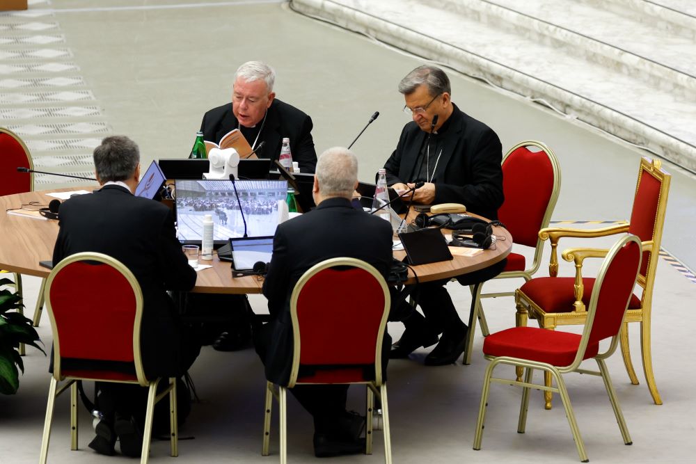 People sit in red chairs around a table. 