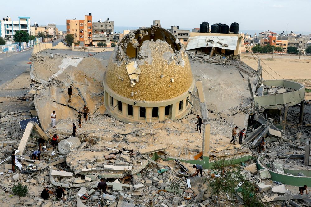 People look at the rubble of a mosque. 
